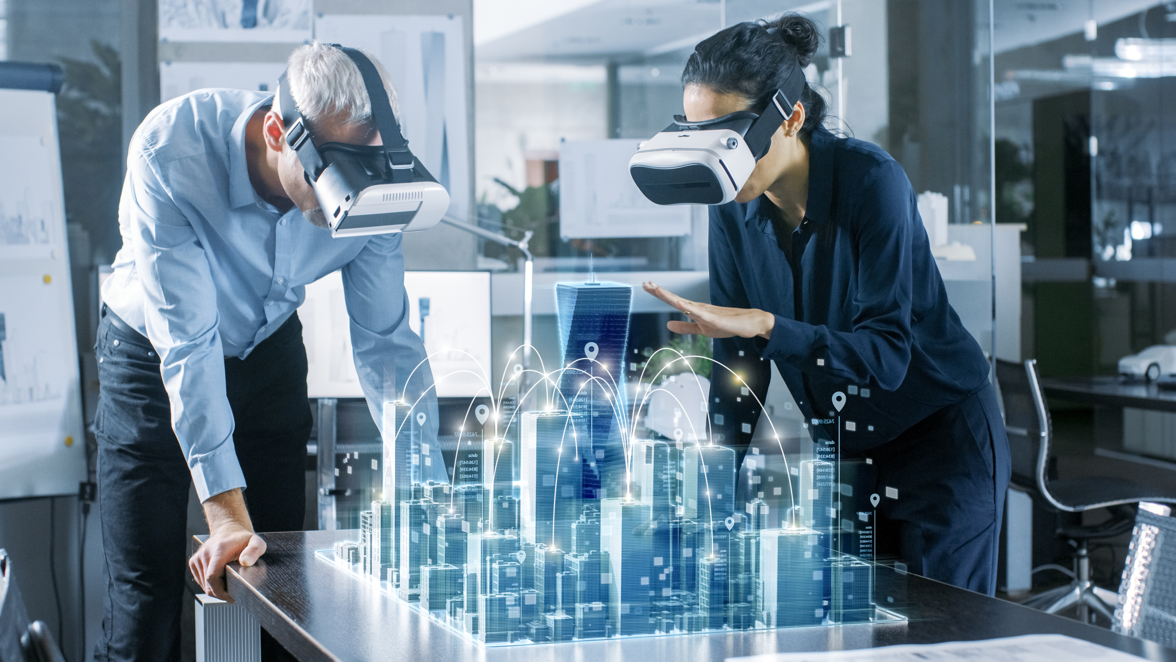 Two people look at a holographic projection of a city.