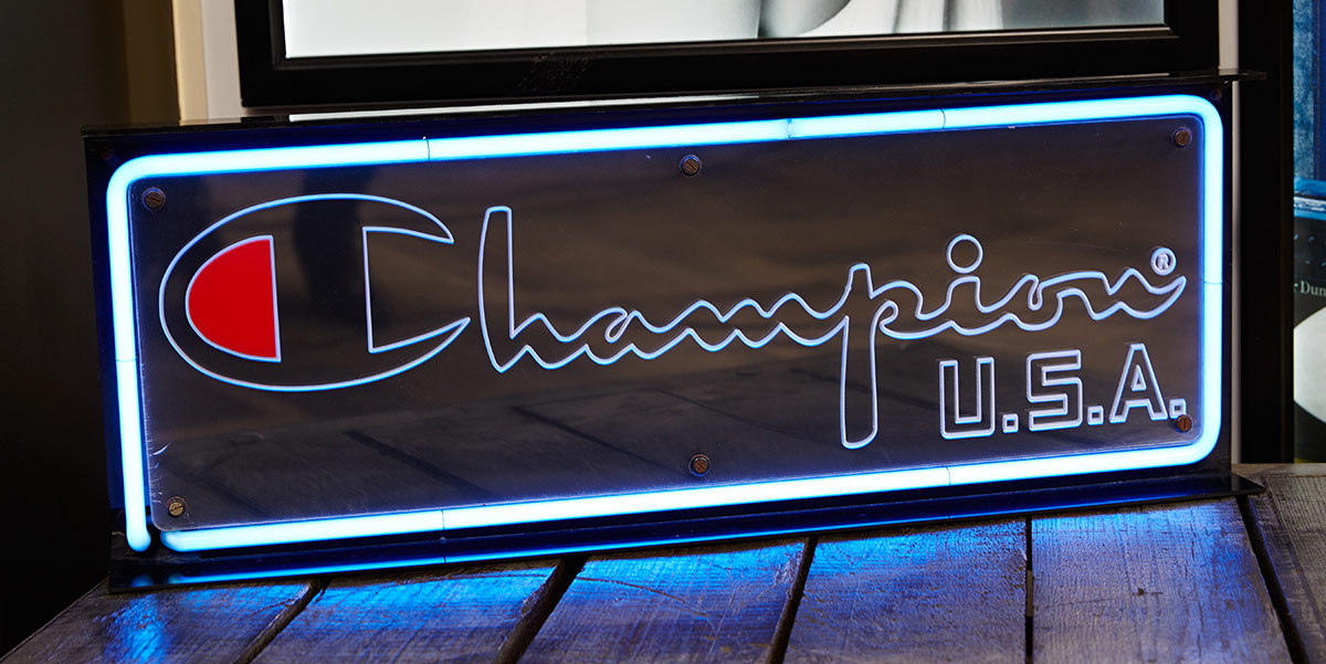 A brightly lit sign with the Champion brand logo displayed.