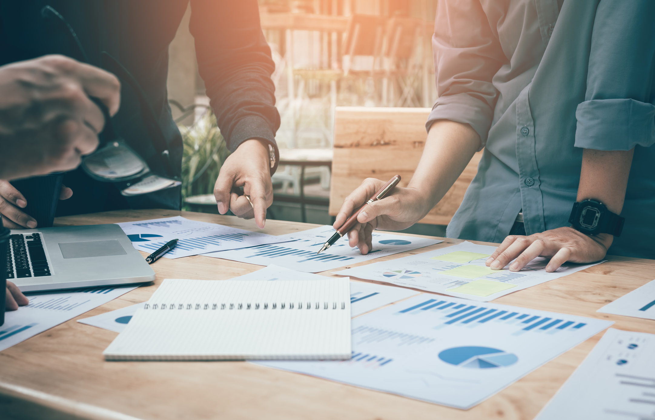 Team of people working on market research with papers and graphs spread out on a desk
