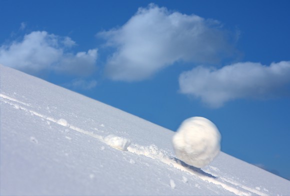 A snowball tumbles downhill and speeds up.