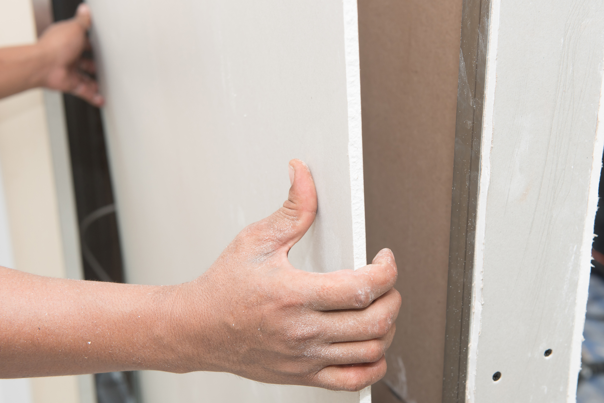 A person hangs drywall.