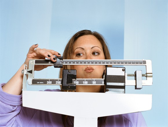 Woman checking her weight on scale.