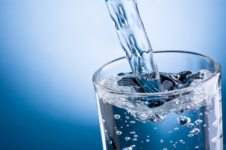 Water pouring into a glass with blue background.