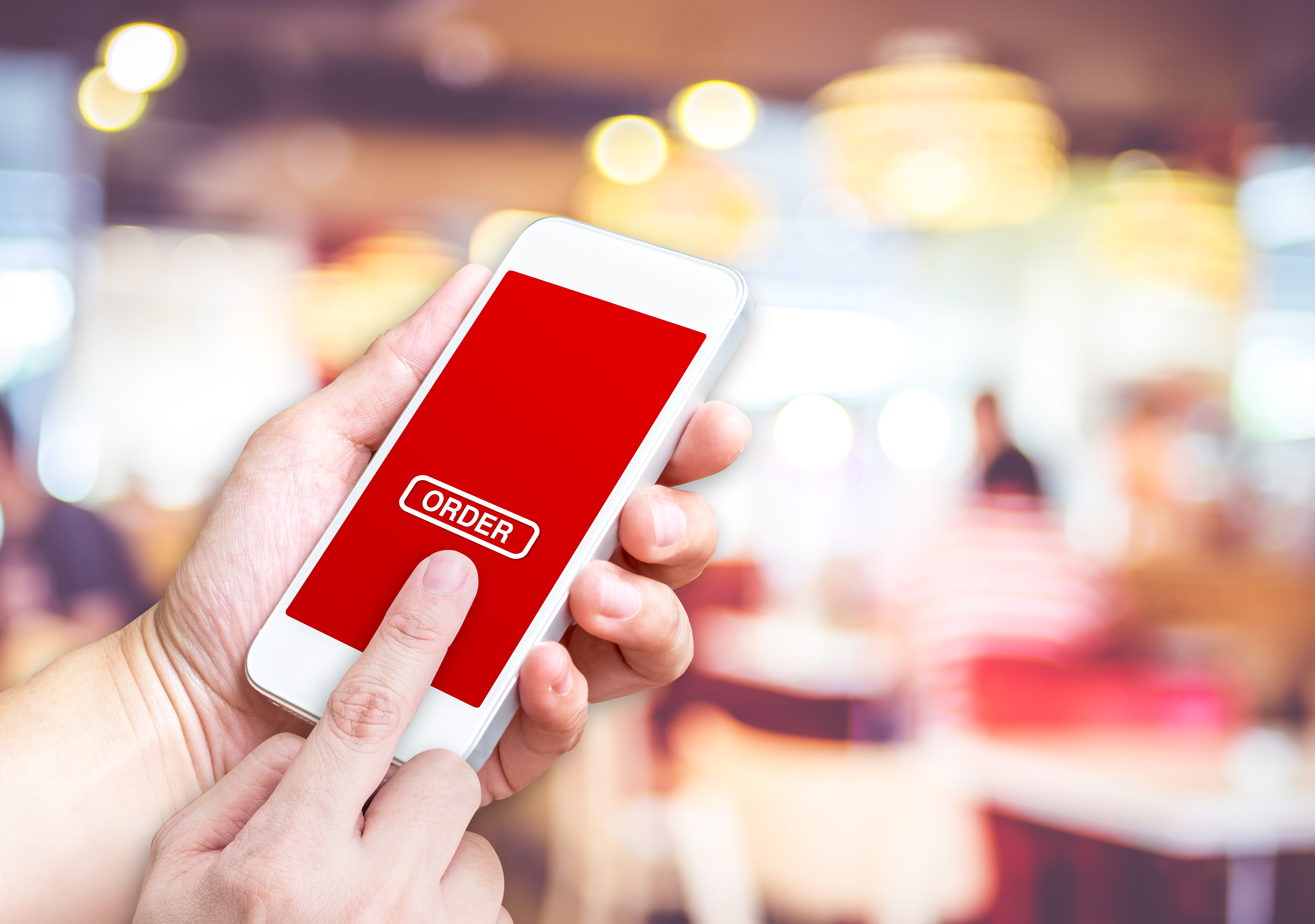 closeup of hands touching an order button on a smartphone screen.