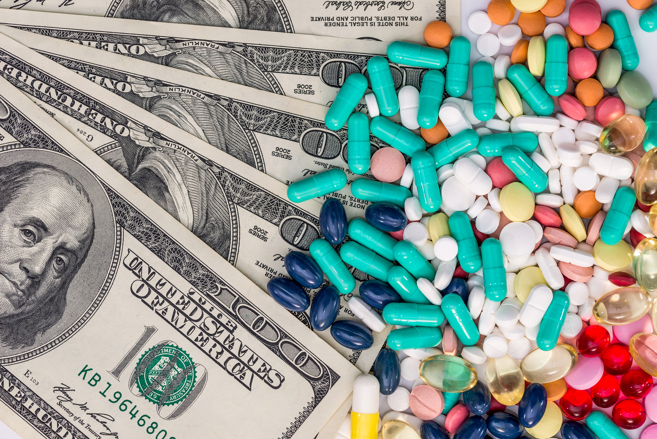 Colored pills on top of $100 bills