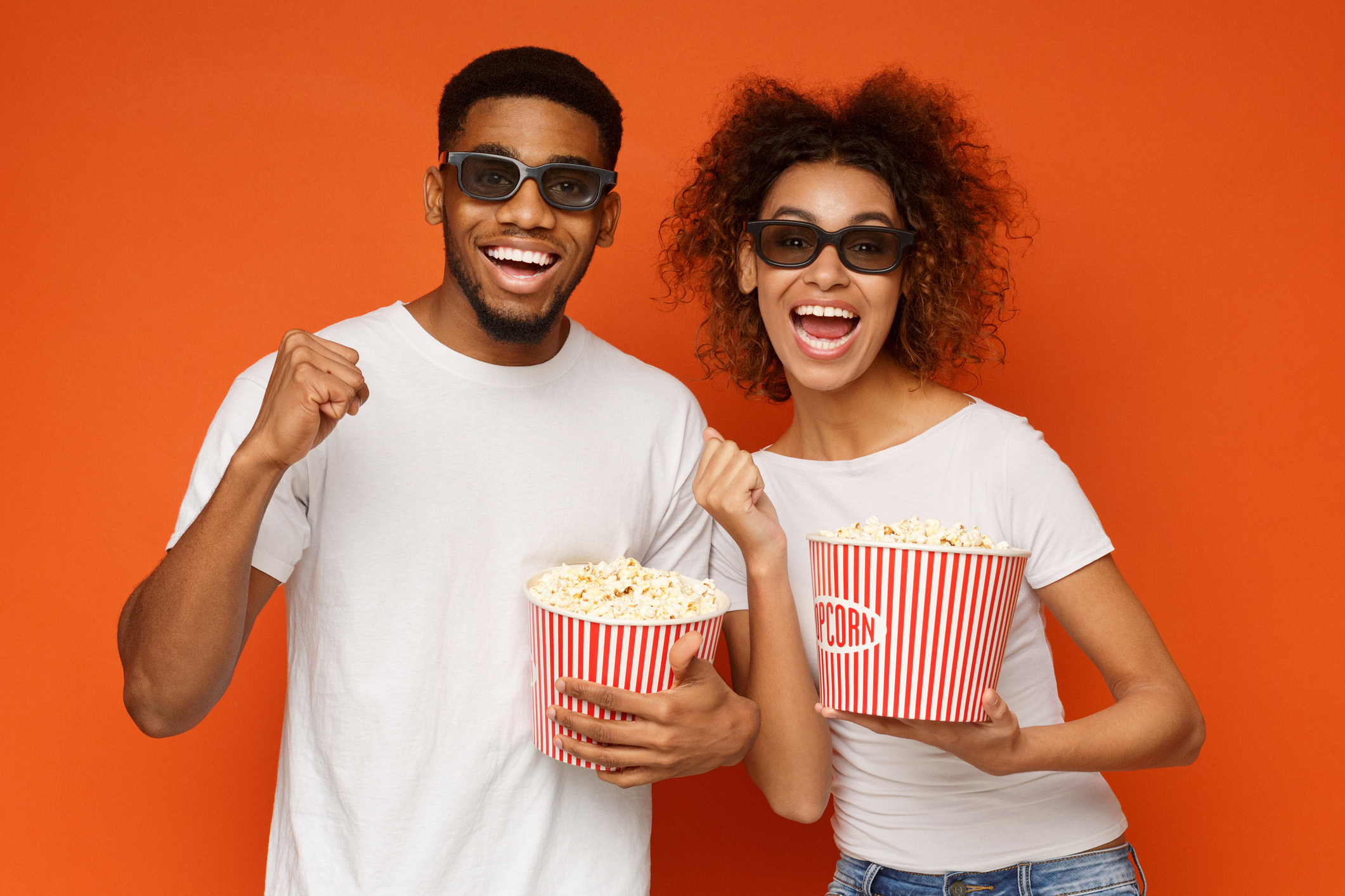 Two moviegoers with popcorn in their hands.