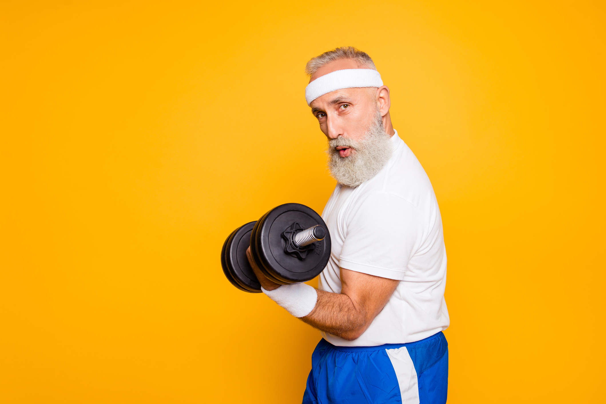 An older man in workout clothes lifting a dumbbell with his arm
