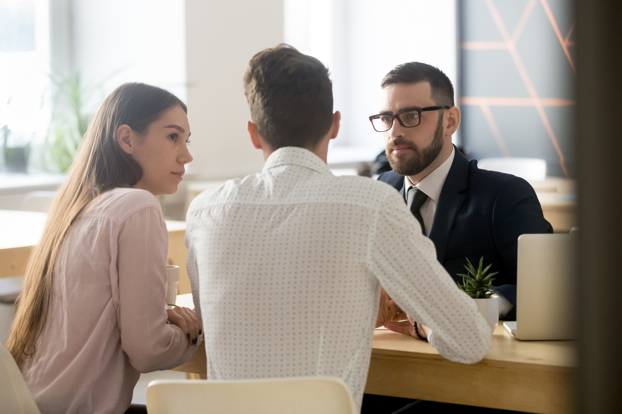Couple sitting across a desk from man in suit.