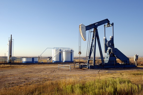 An oil pump next to some storage tanks