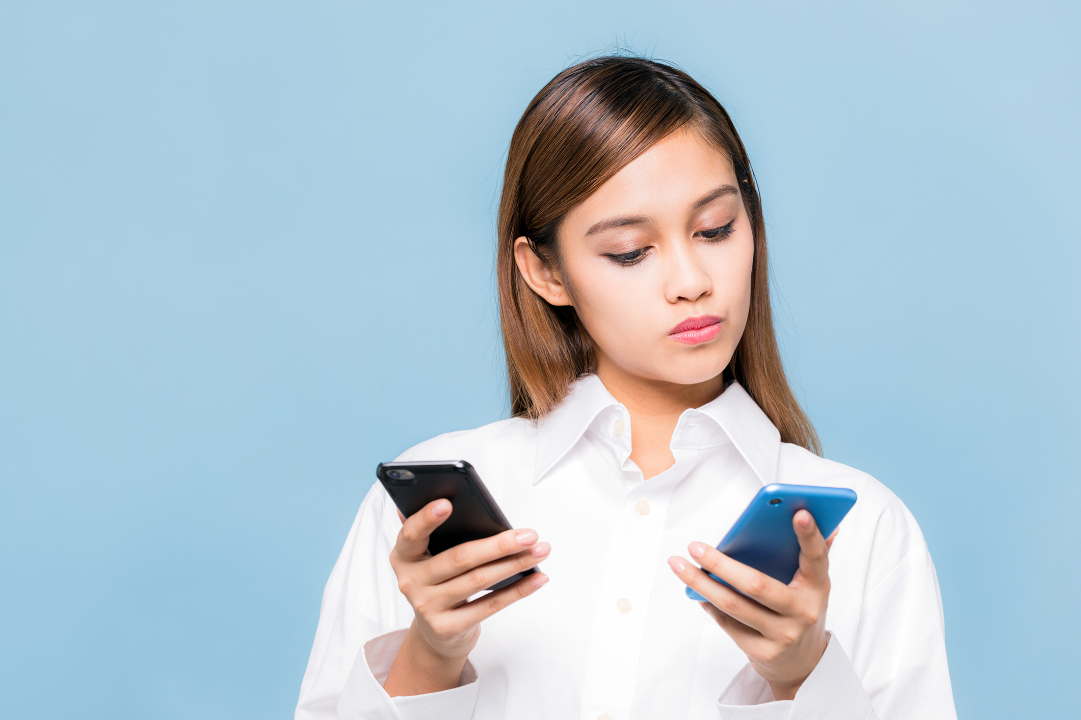 Woman looking at two phones.