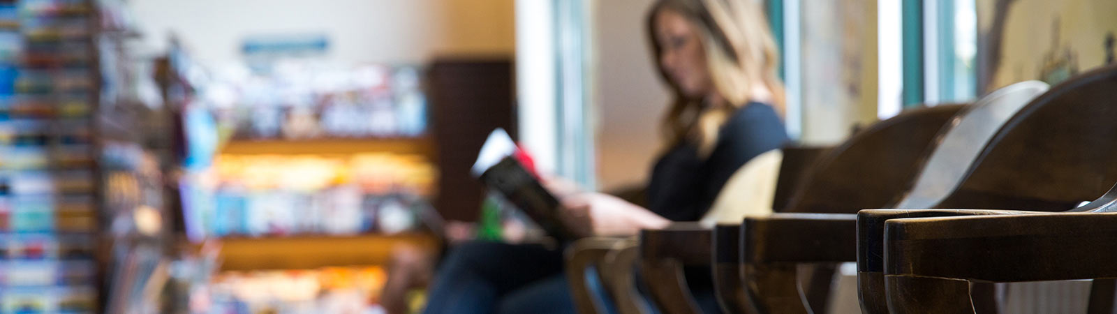 A woman sits and reads a book in a bookstore.