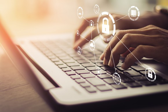 A person typing on a laptop of with digital images of locks over it.