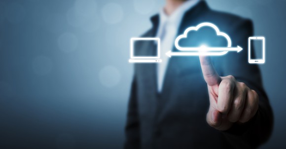 A businessman's hand pushing a cloud icon on a screen