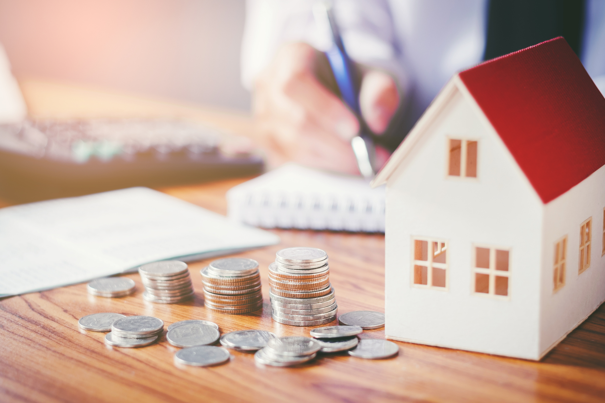 Miniature house with stacks of coins next to it.