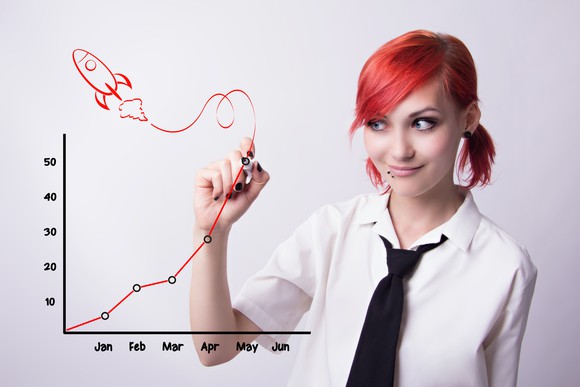 A young woman draws a rocket soaring from an ascending line graph.