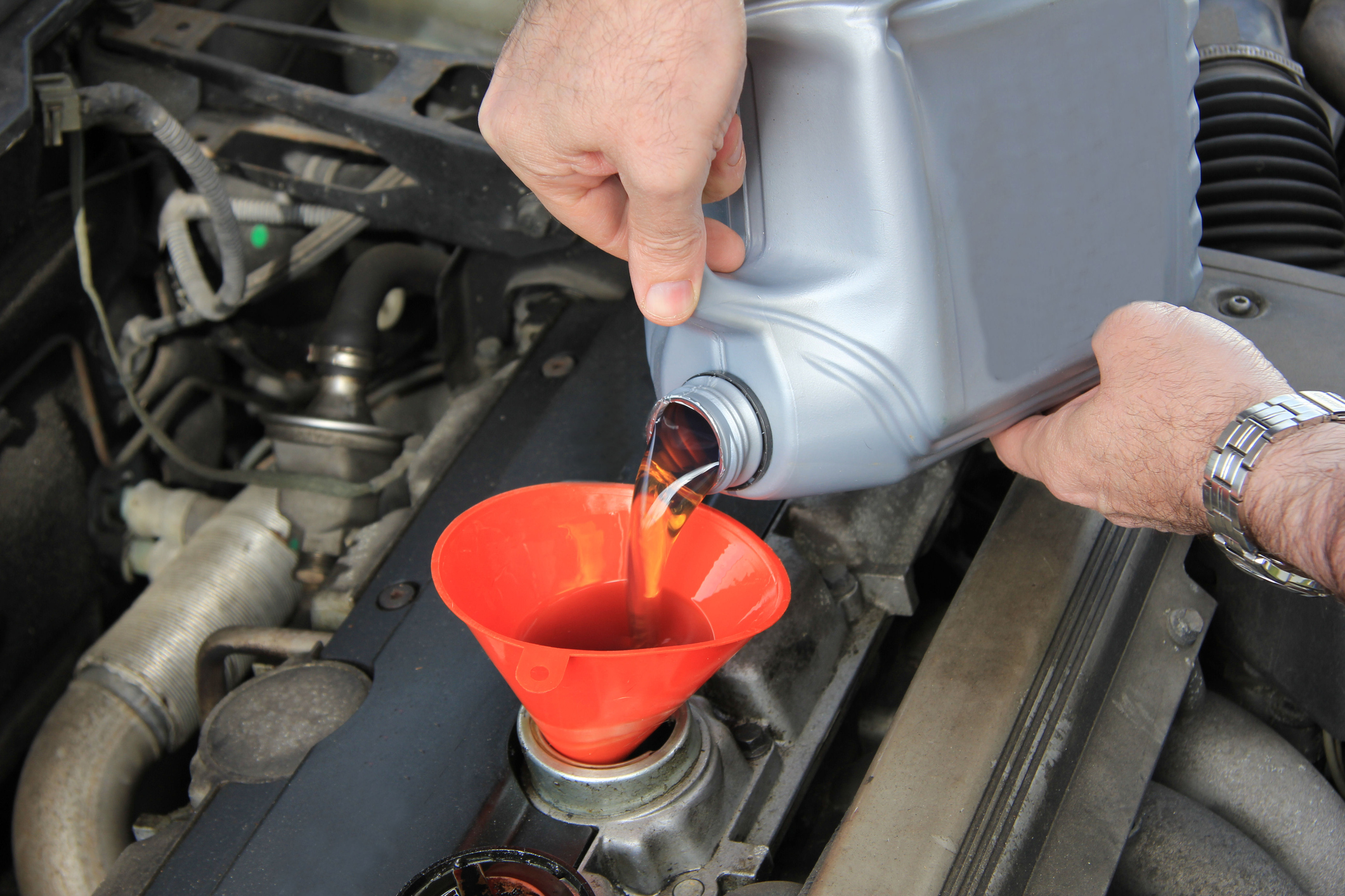 Adding motor oil to an auto engine.
