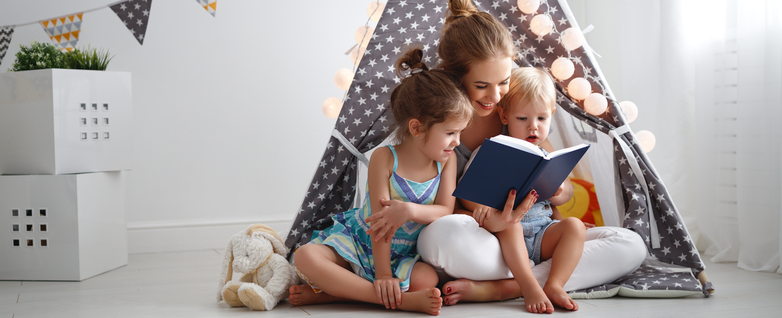 Woman reading to a young girl and boy.