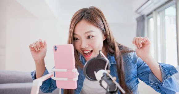 A young woman broadcasts a live video on her smartphone.