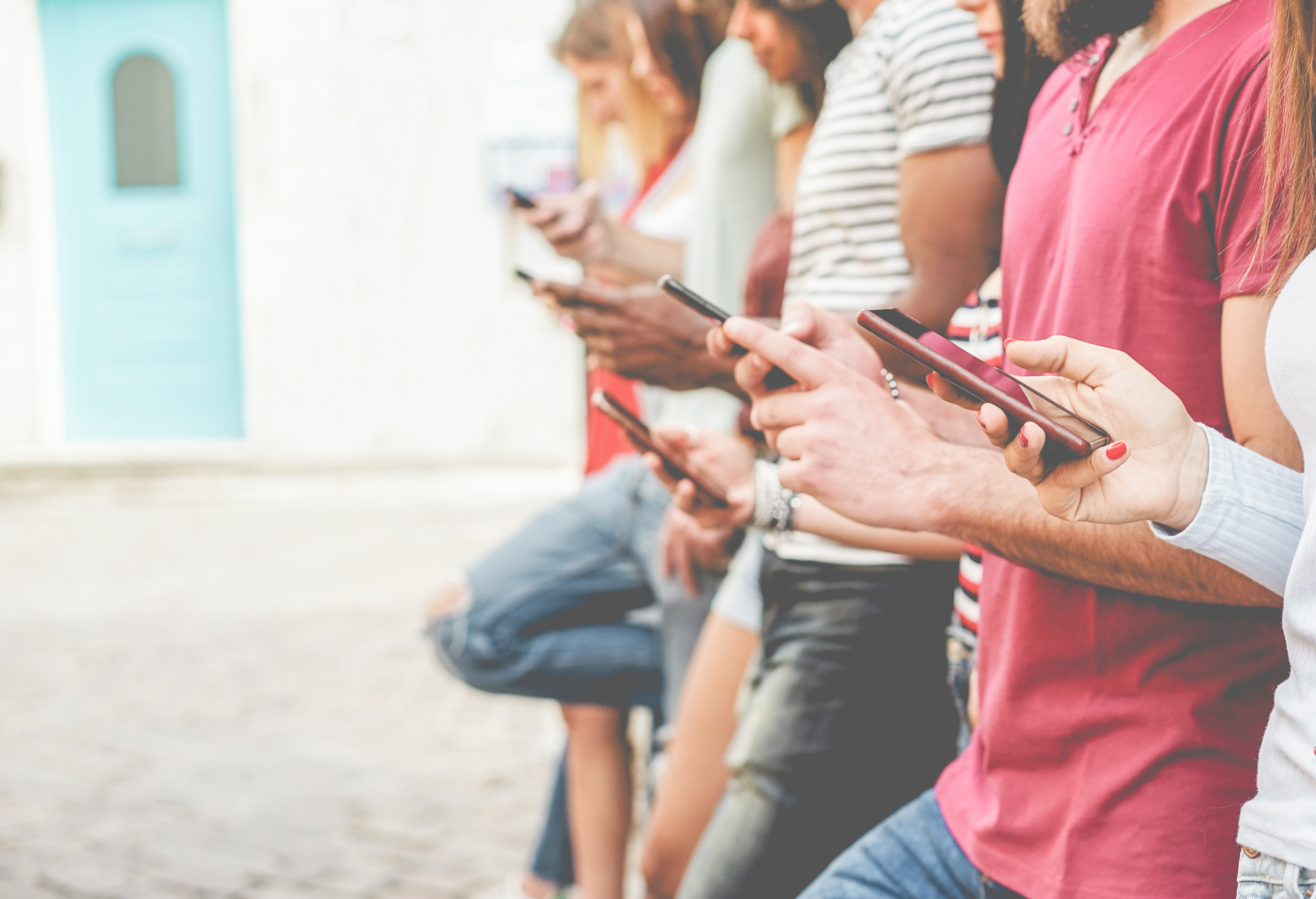 A line of people all looking at their smartphones.