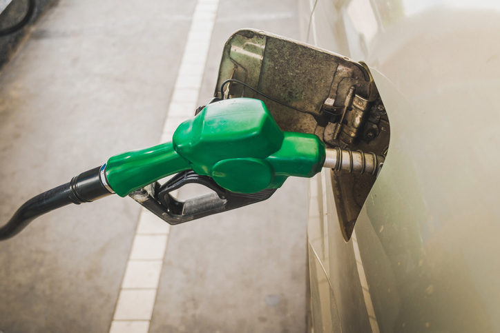 A green fuel pump inserted into a vehicle's gas tank