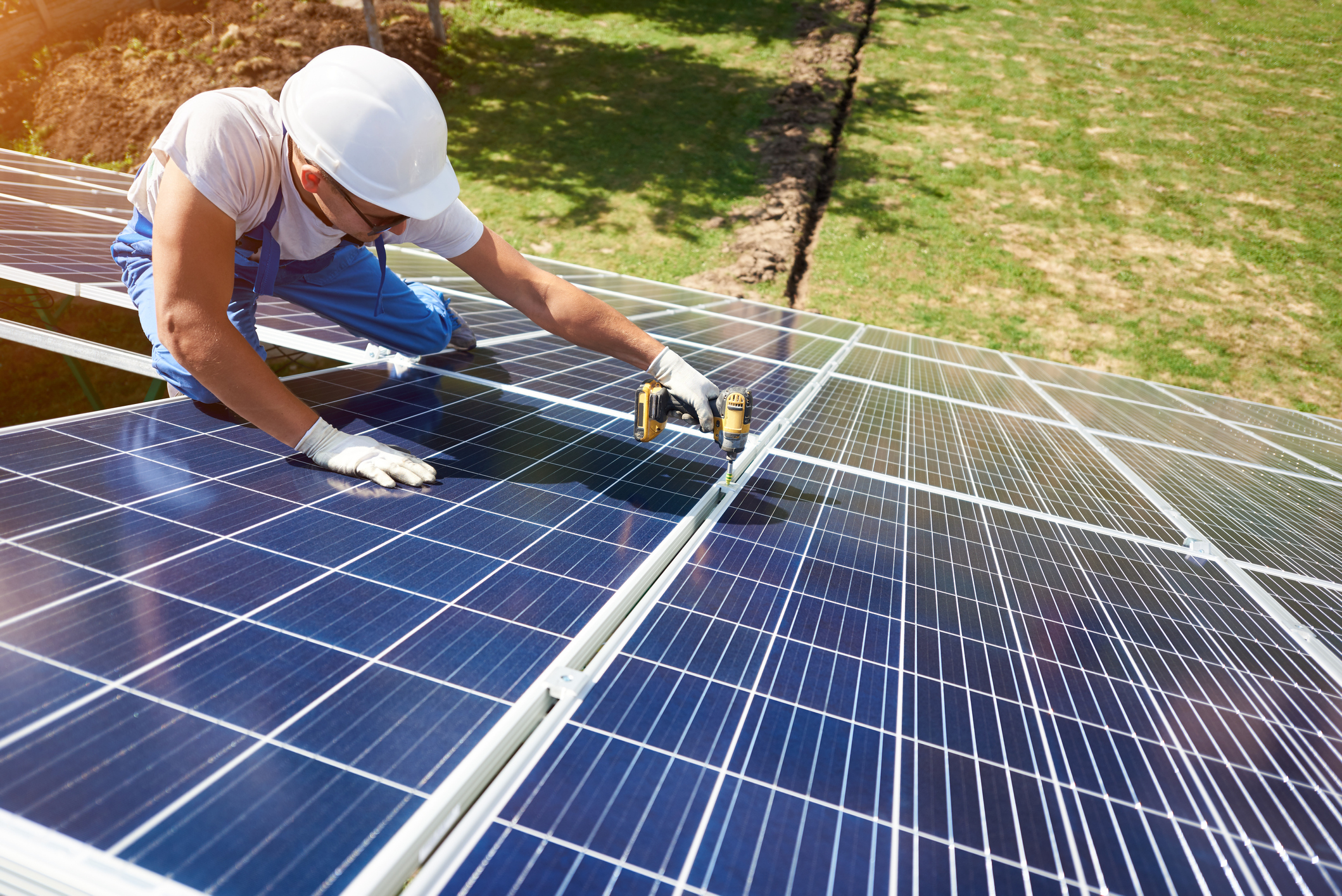 A man uses a cordless drill on a solar panel.