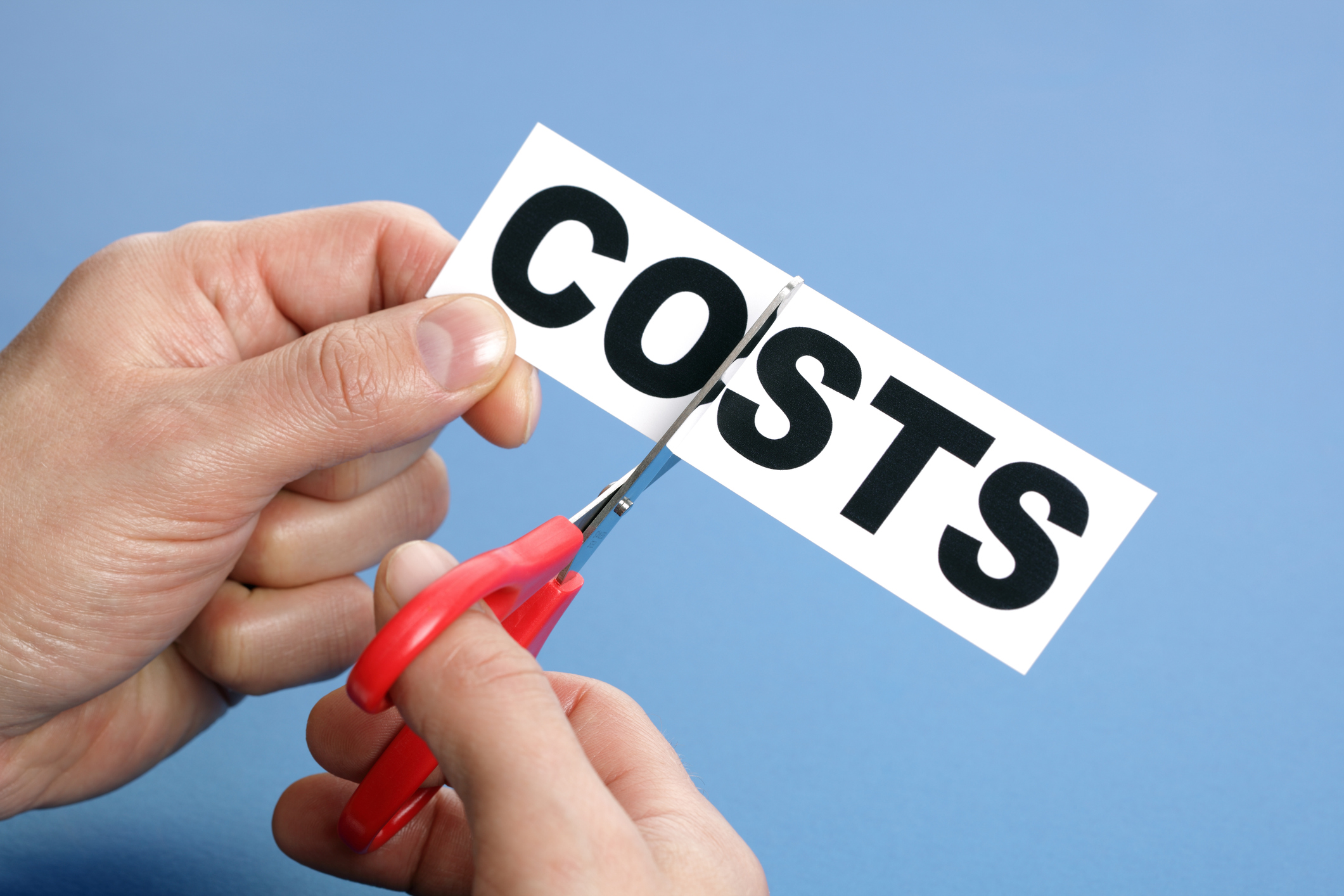 Scissors cutting a piece of paper with the word costs.