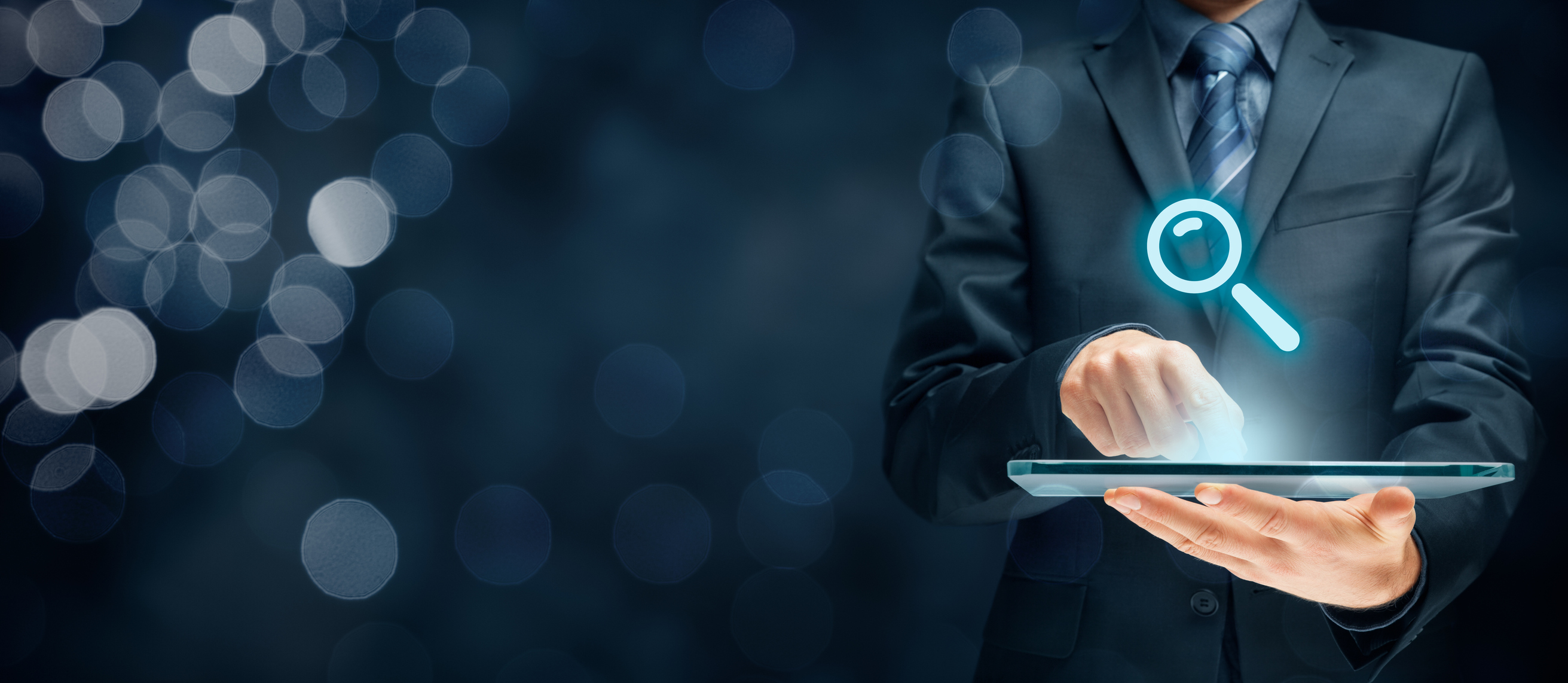 A man holding a tablet displaying a magnifying-glass icon.