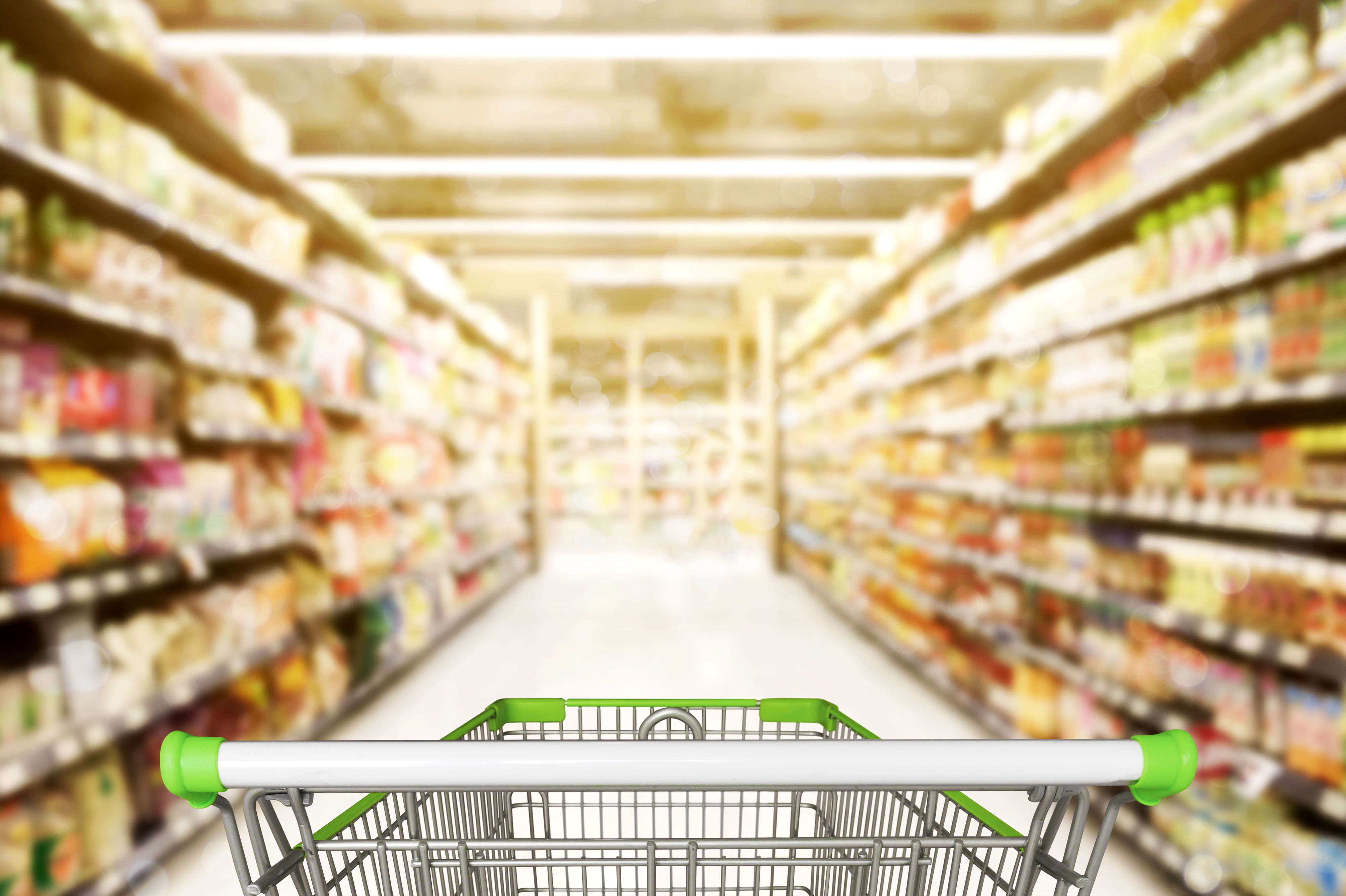 An empty shopping cart in a supermarket aisle.