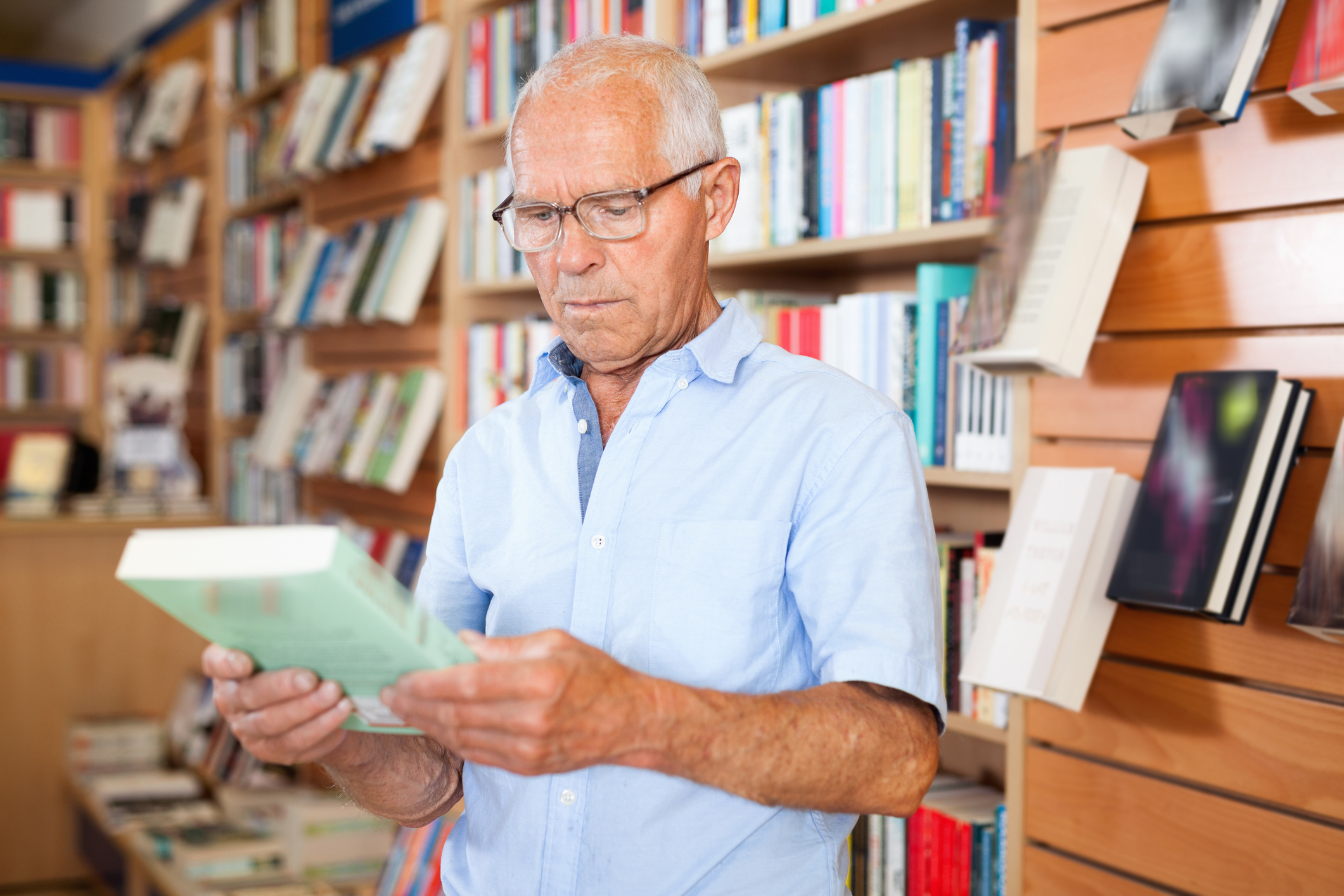 Senior man in bookstore holding book