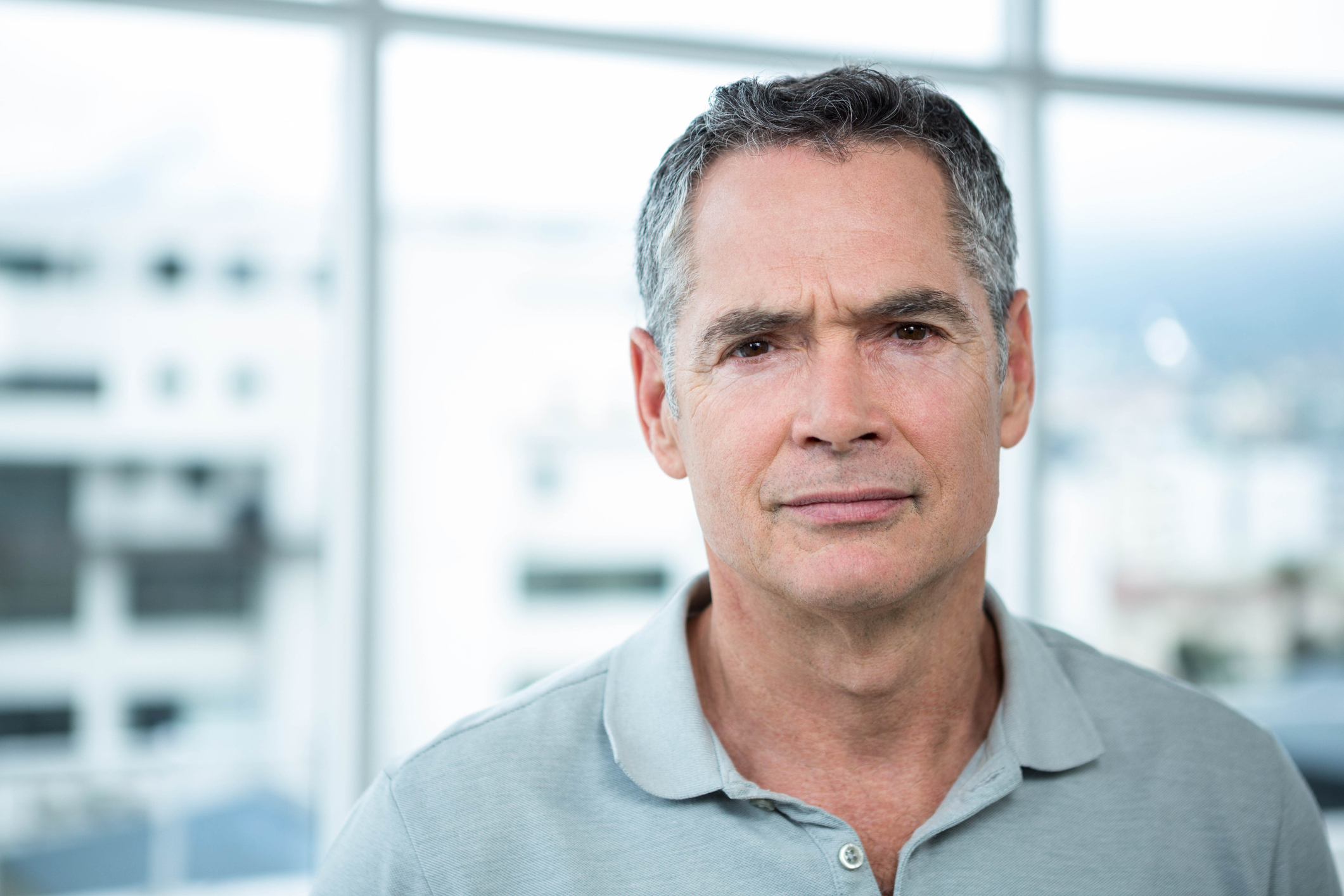 Closeup of gray-haired older man in polo shirt with serious expression