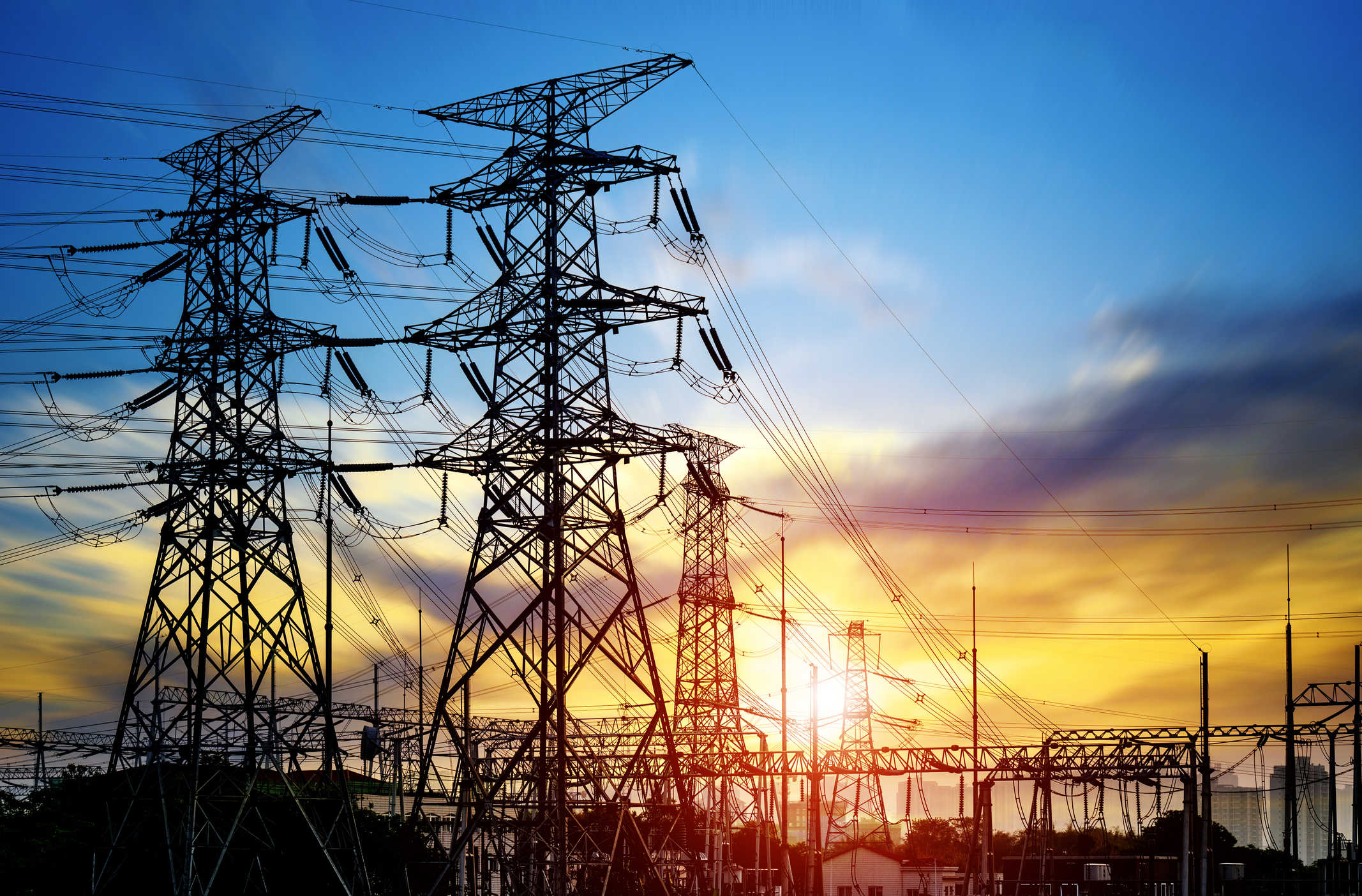 Electric transmission wires in front of a sunset.