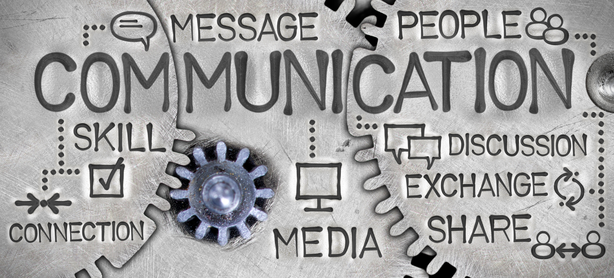 Macro photo of tooth wheel mechanism with COMMUNICATION concept related words and icons imprinted on metal surfac