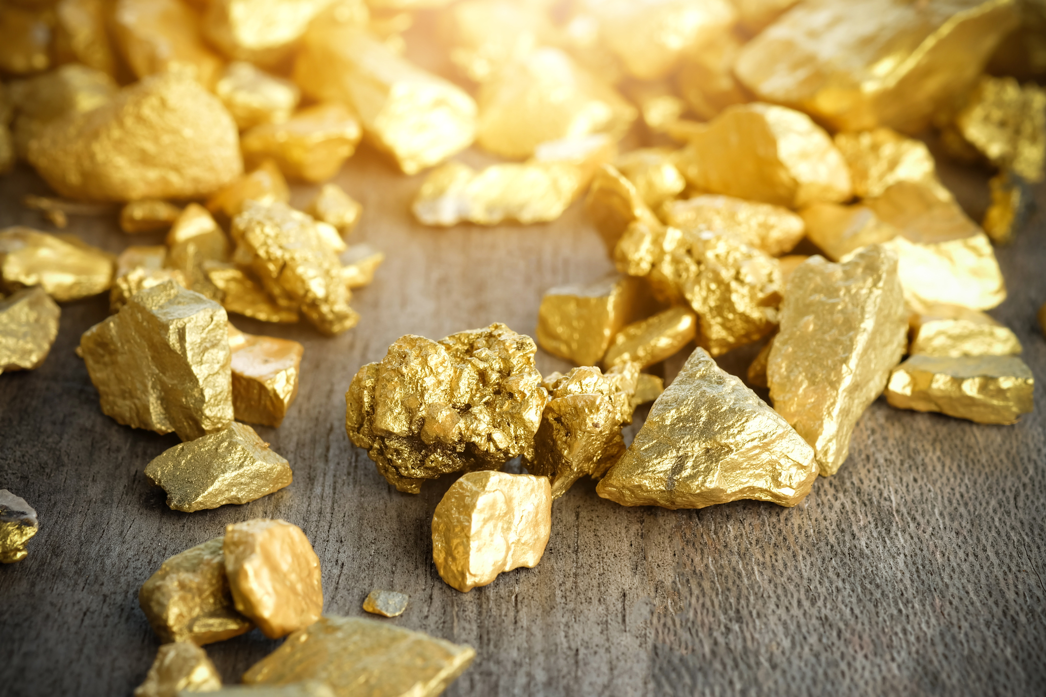 Shimmering gold nuggets on a wooden table.
