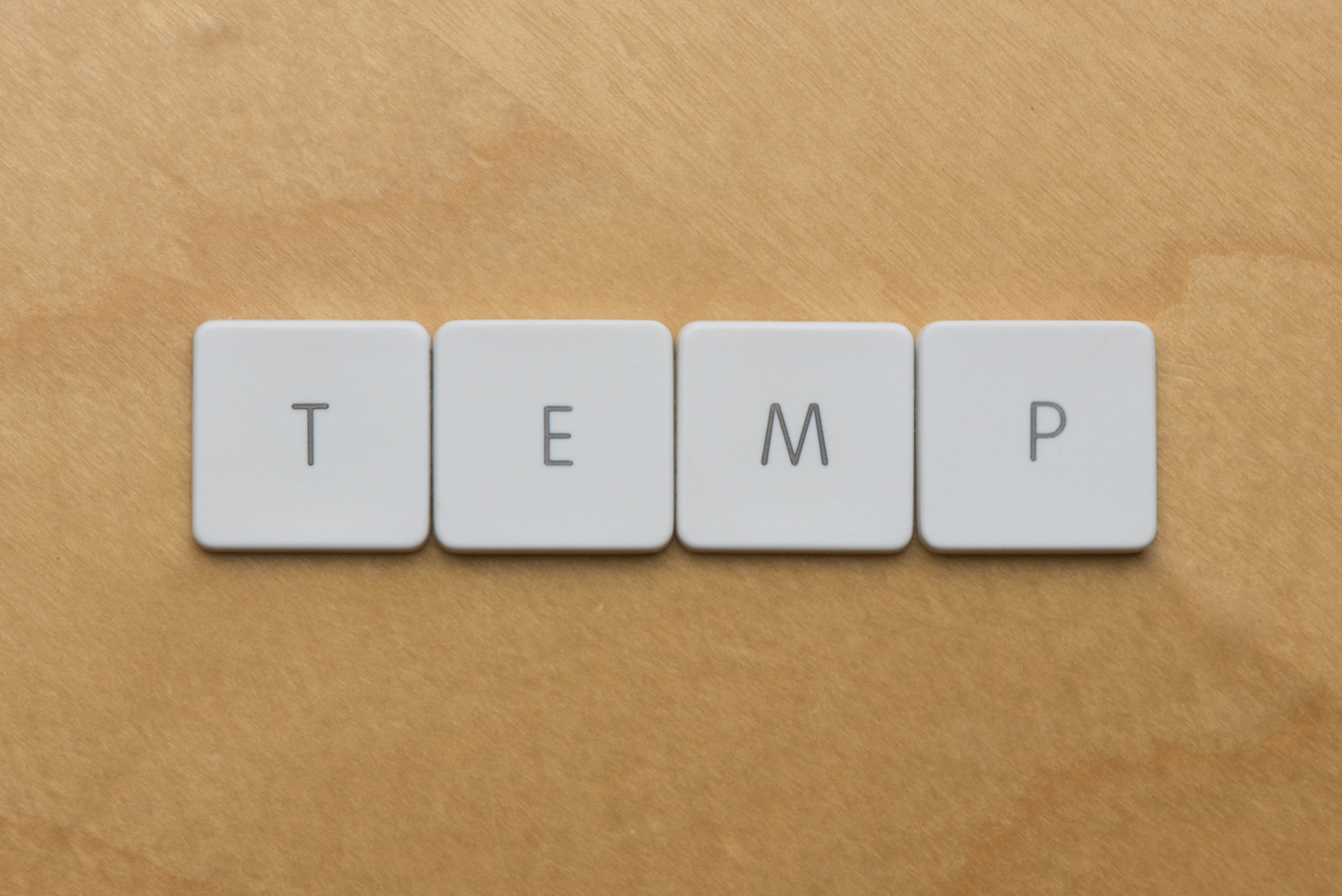 The word "temp" spelled out in tiles against sand-colored background.