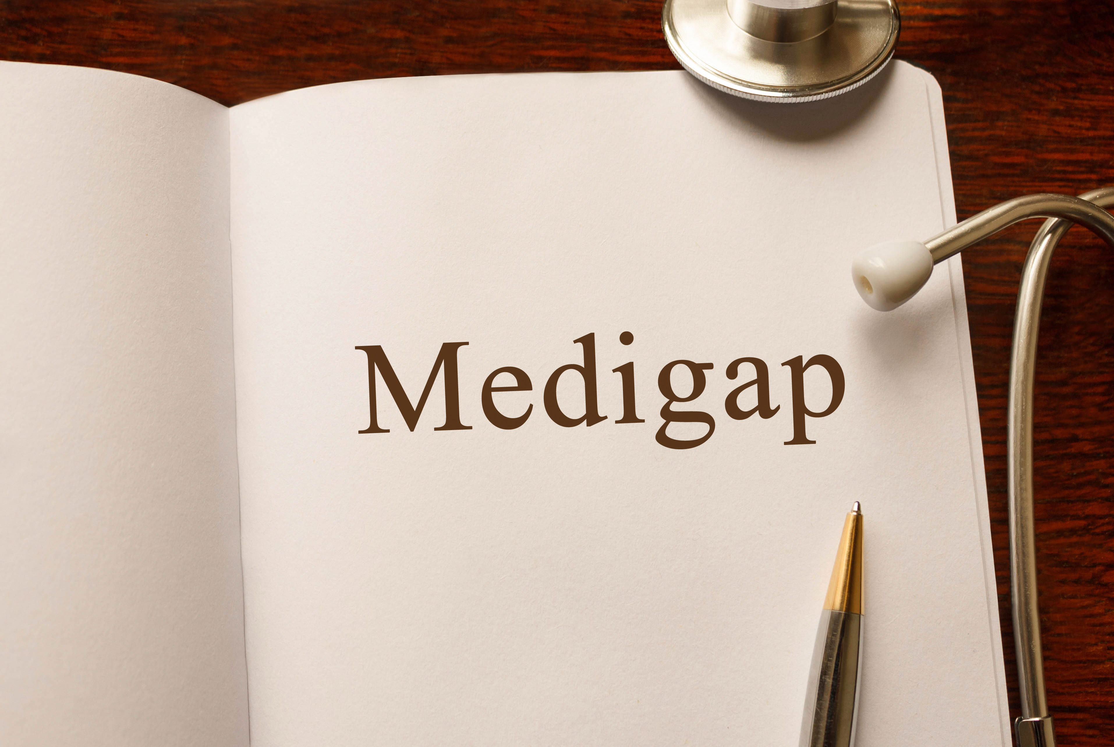 Notebook open to a page that says Medigap, with a pen resting on it