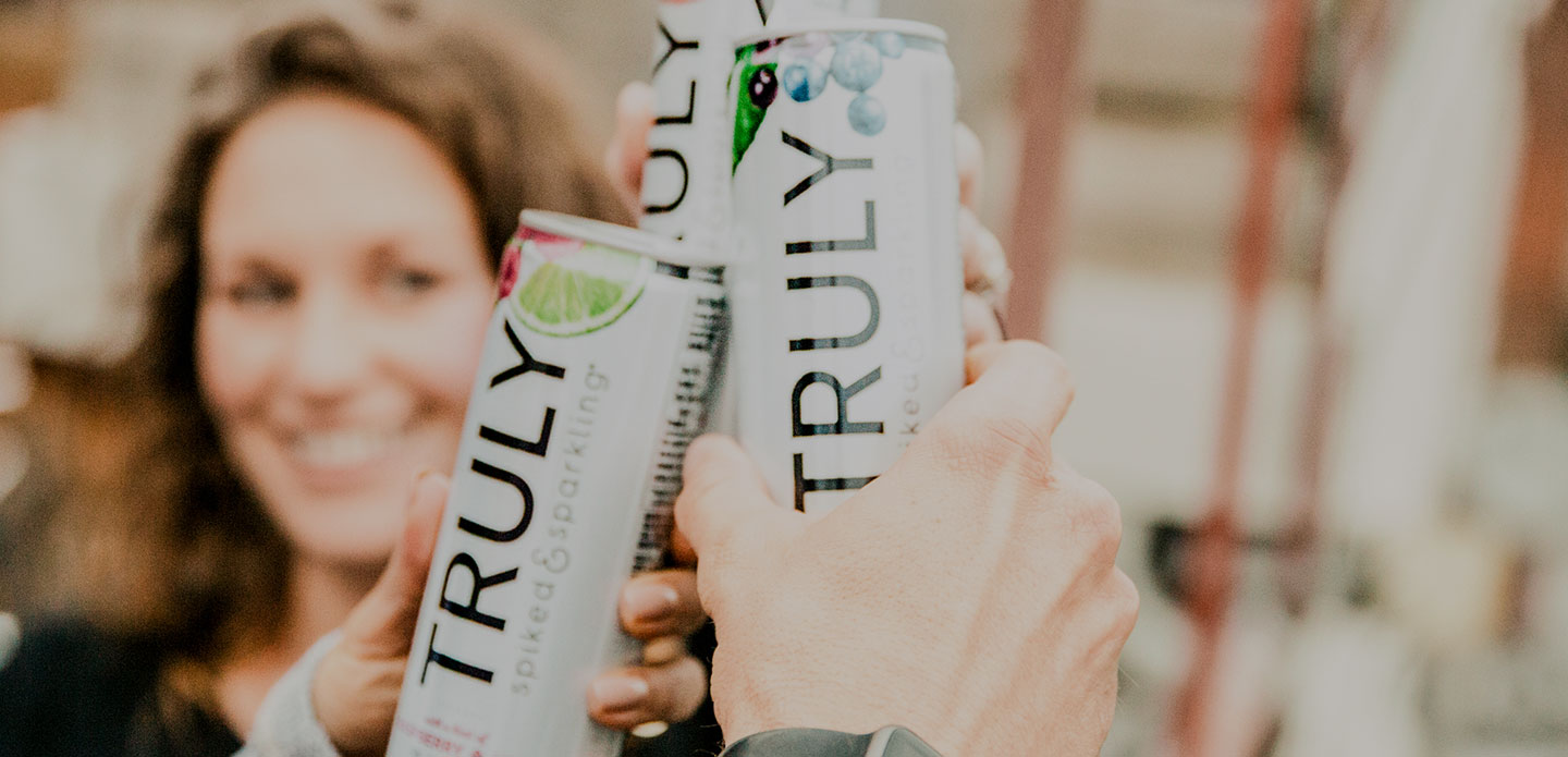 People toasting with Truly hard seltzer cans