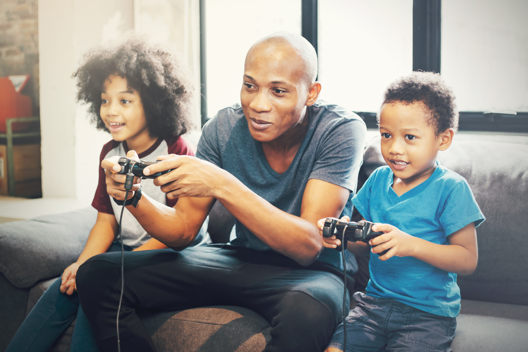 Family playing video games on a couch.