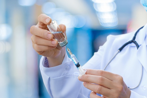 physician drawing up a medication from a vial