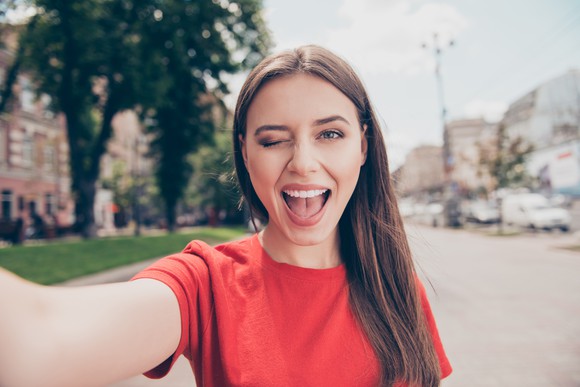 A young woman winks while taking a selfie.