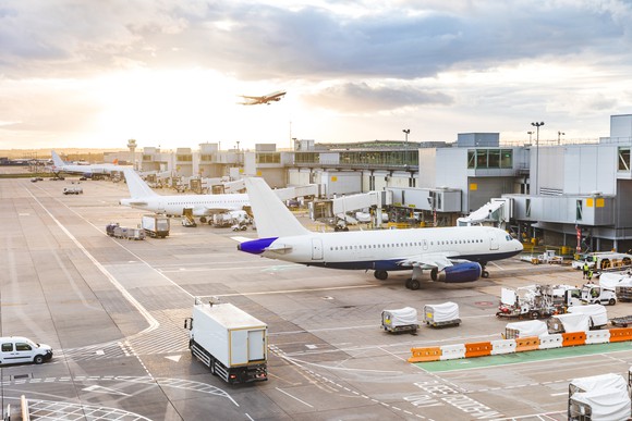 Busy airport scene with planes and service vehicles.
