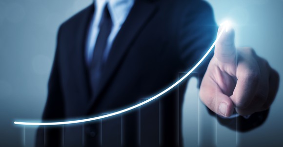 A businessperson pointing to an upwardly-sloping chart