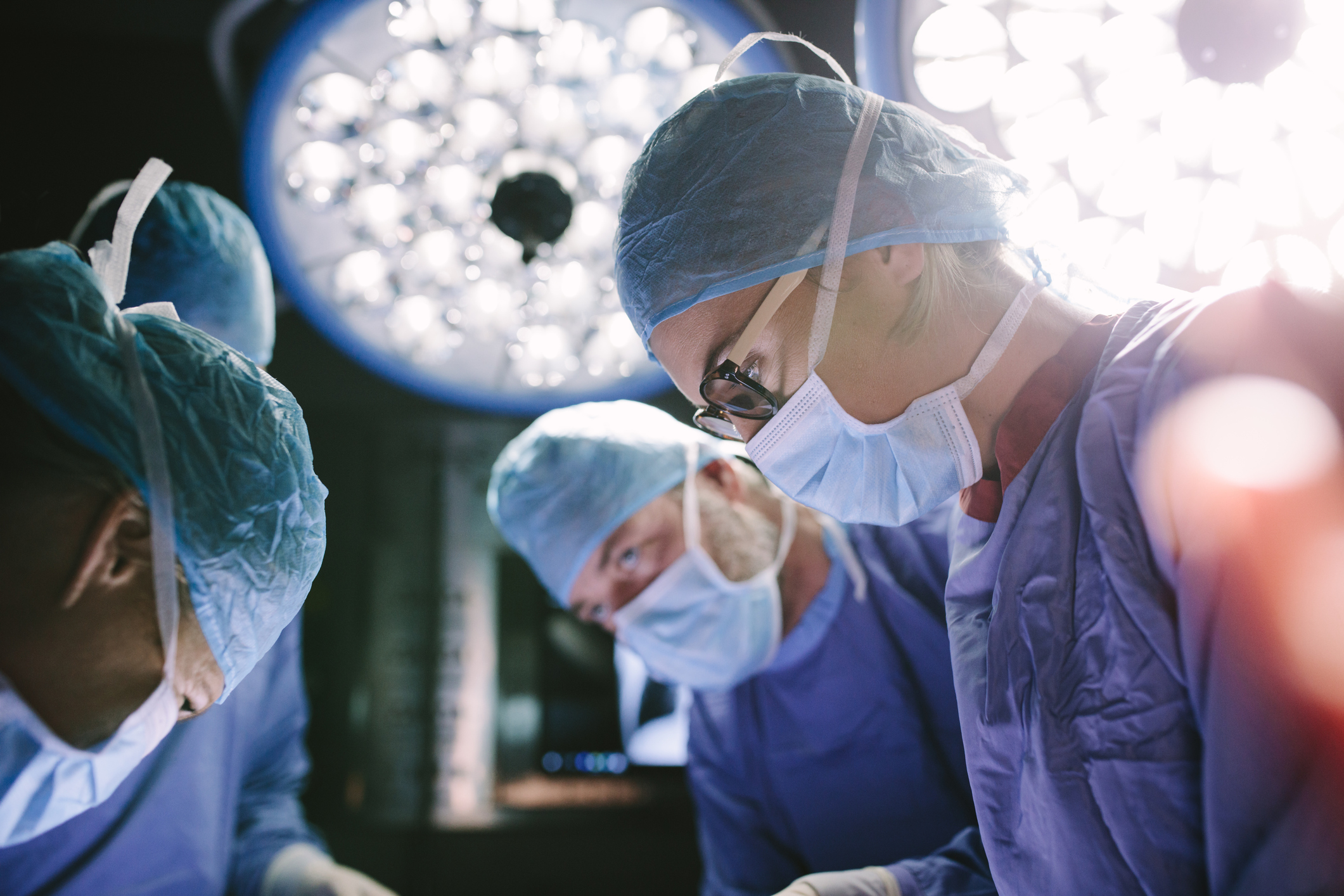 Surgeons in operating room with lights over their heads.
