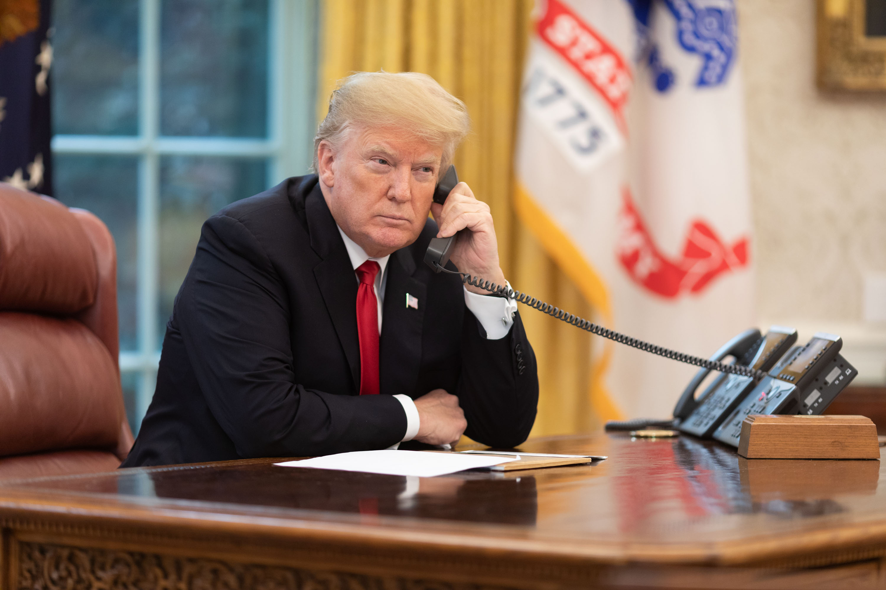 President Trump talking on the phone in the Oval Office.