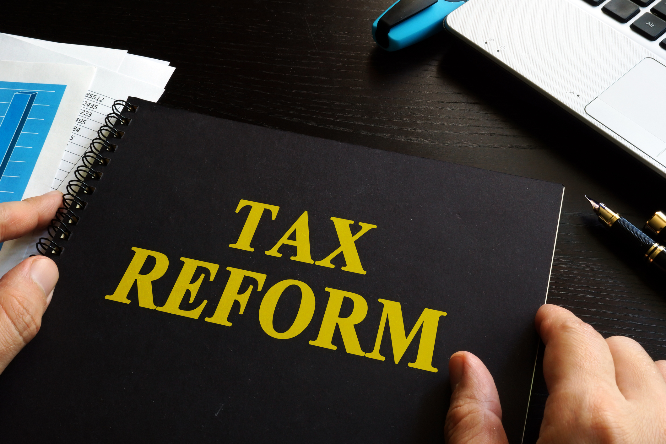 A person holding a binder labeled with the words, tax reform.