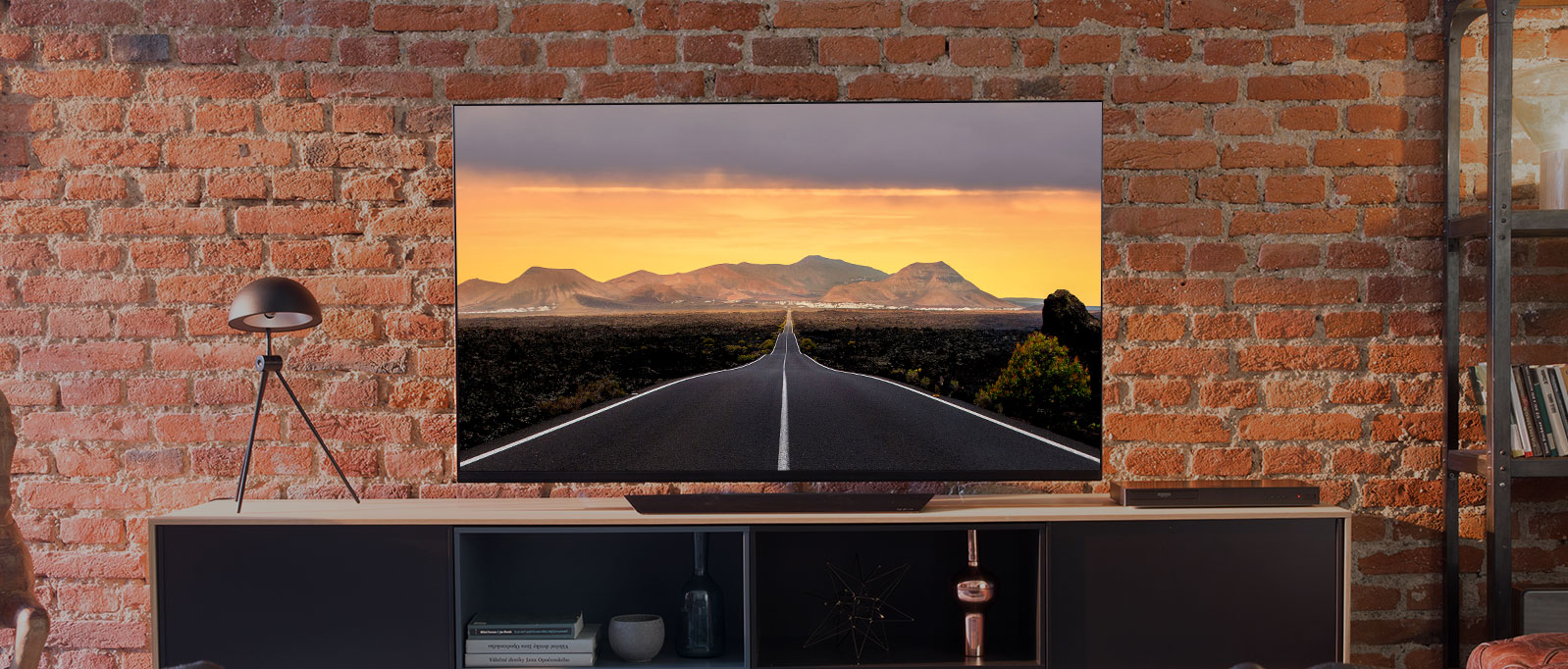 An LG OLED TV on an entertainment stand against a brick living room wall.