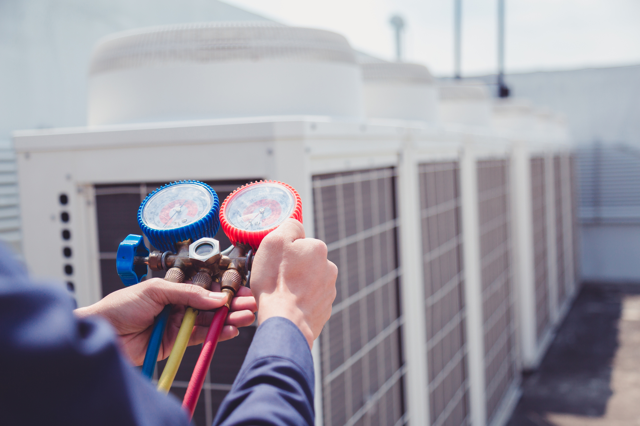 An air conditioner repair technician checks the levels on an outdoor unit.