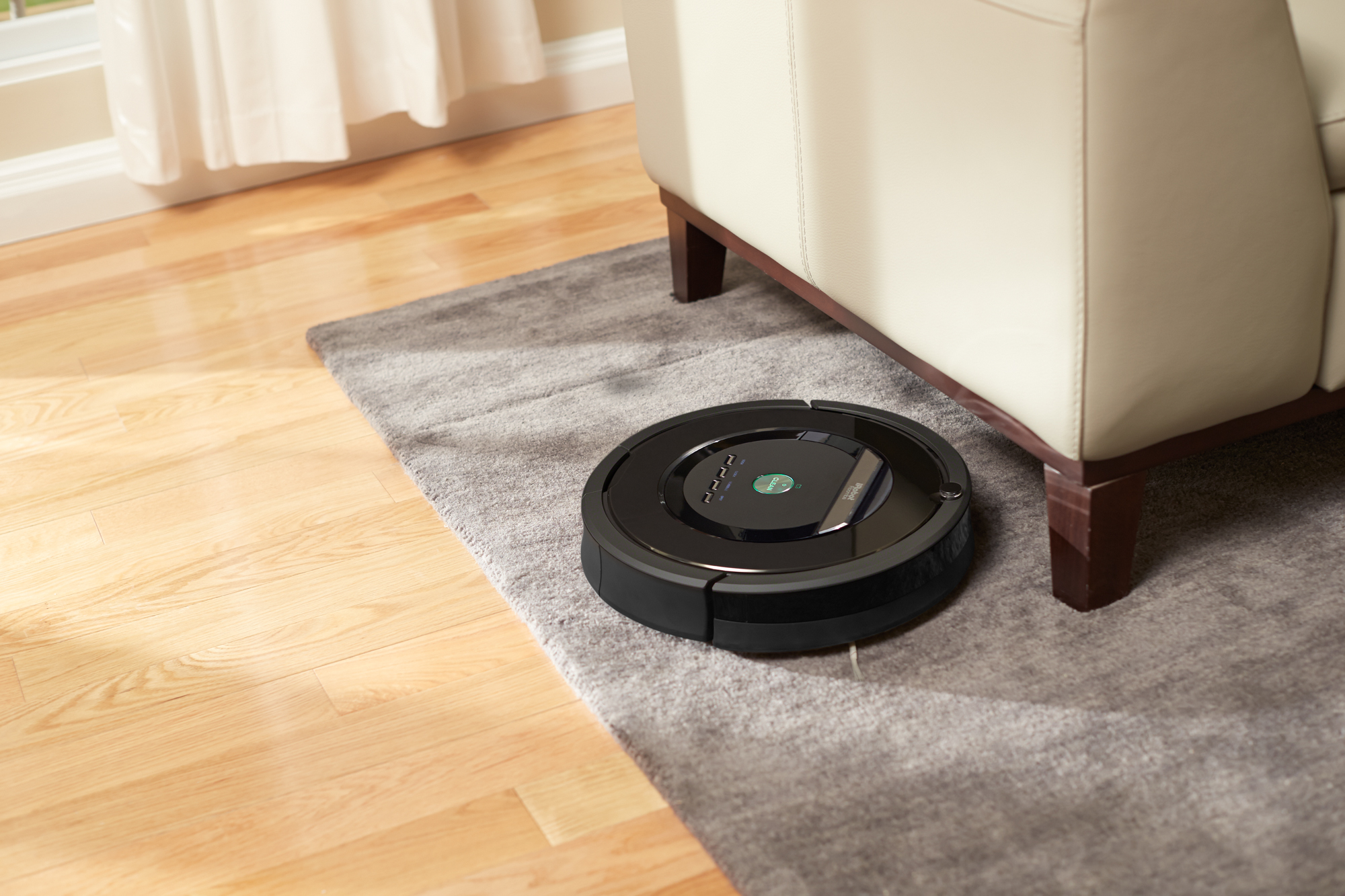 Roomba cleaning a carpet near a couch