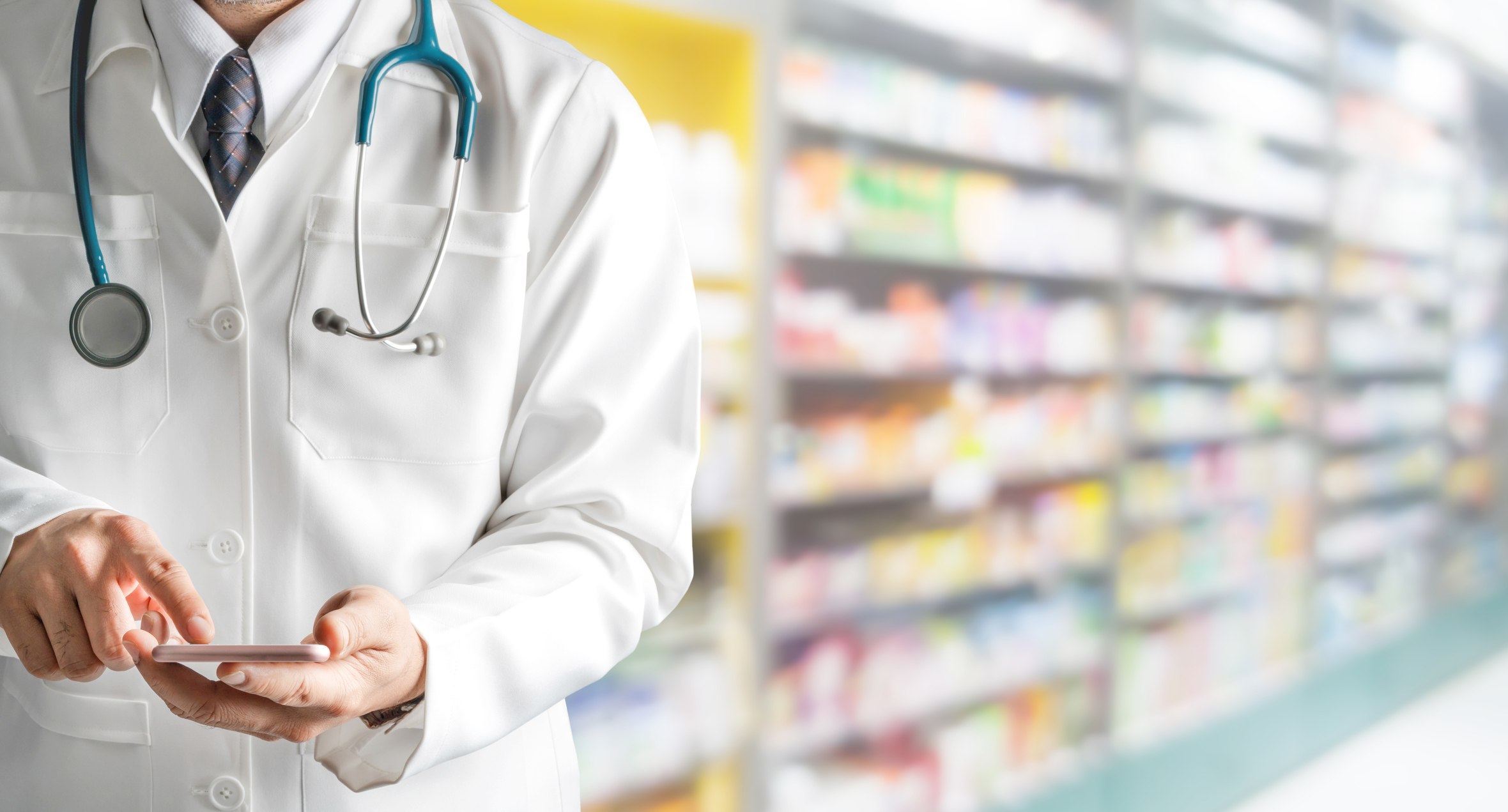 Pharmacist holding phone with drug shelves in background