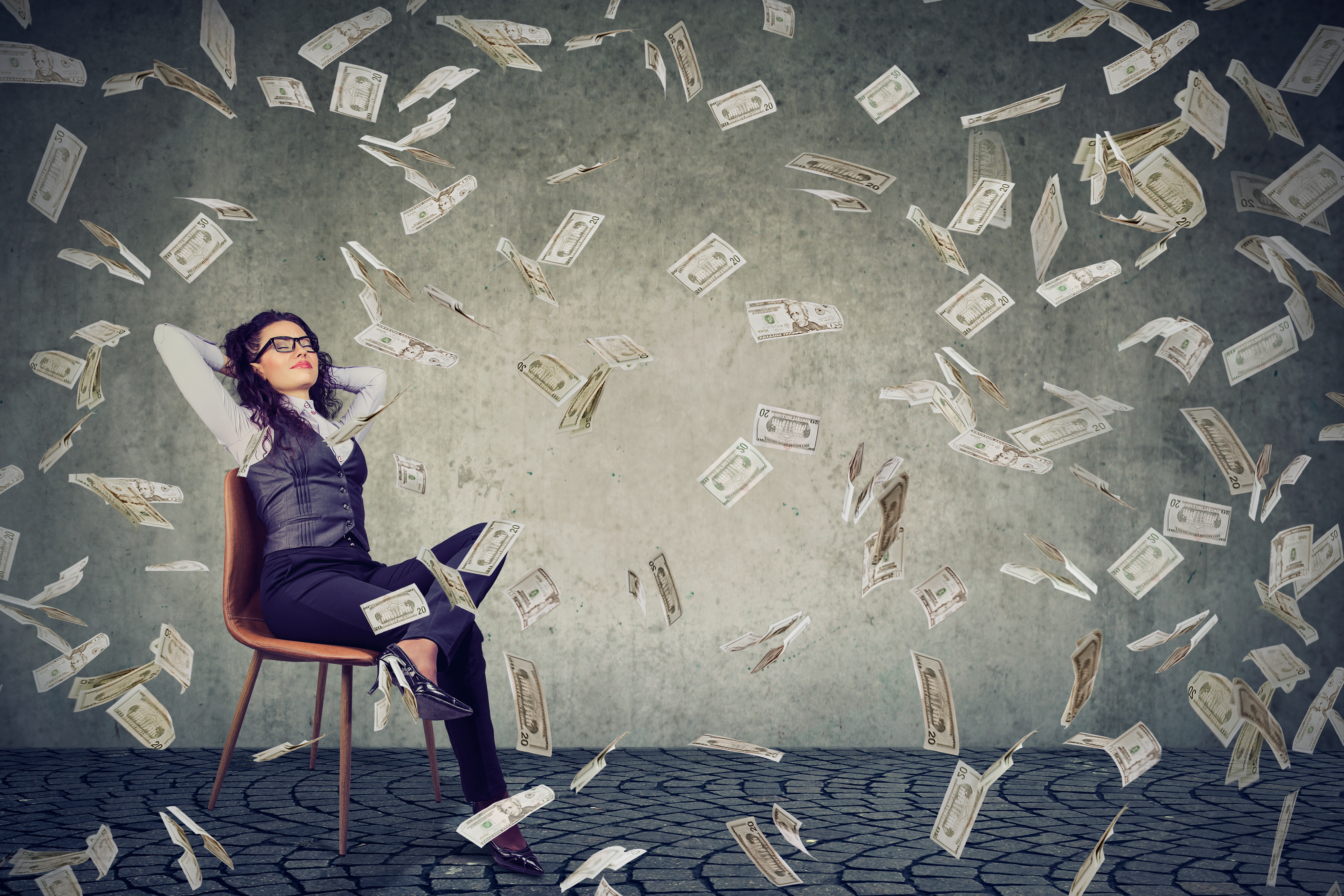 Woman sitting on a chair with money blowing around her.