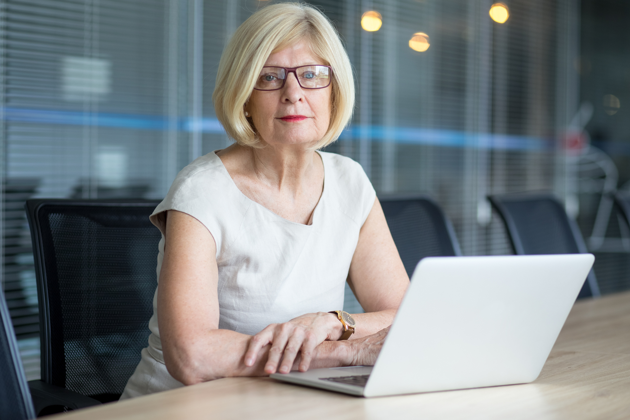 A female executive sitting at a conference room table with her laptop in front of her.